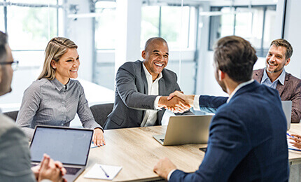 Two men shake hands at a team meeting