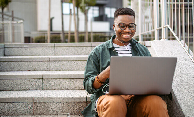 Man in headphones sitting on stairs with a laptop