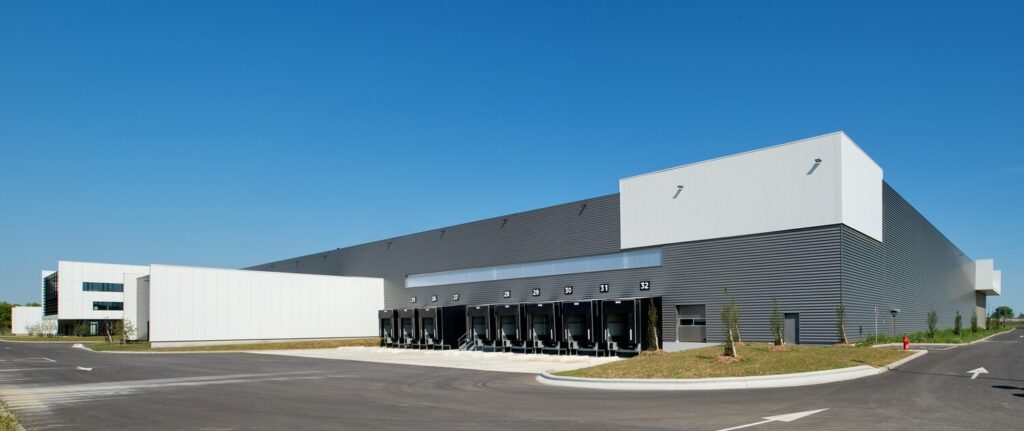 A large gray and white warehouse with a place for loading trucks