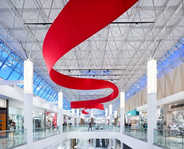 Installation resembling a red ribbon on the ceiling inside a shopping center