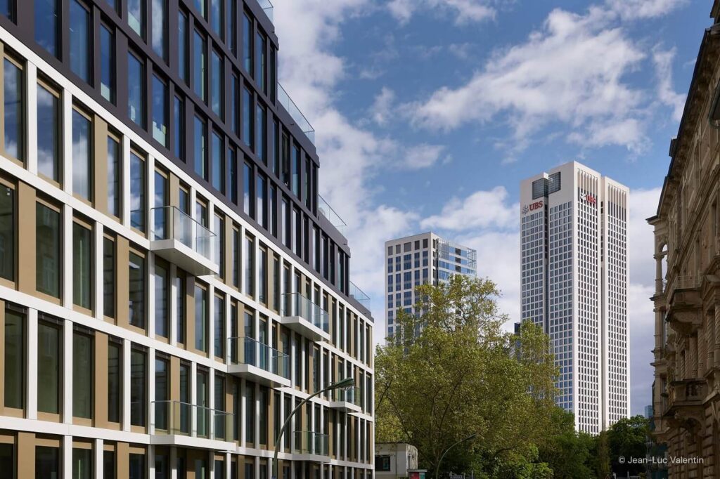 A large glass building with skyscrapers in the background