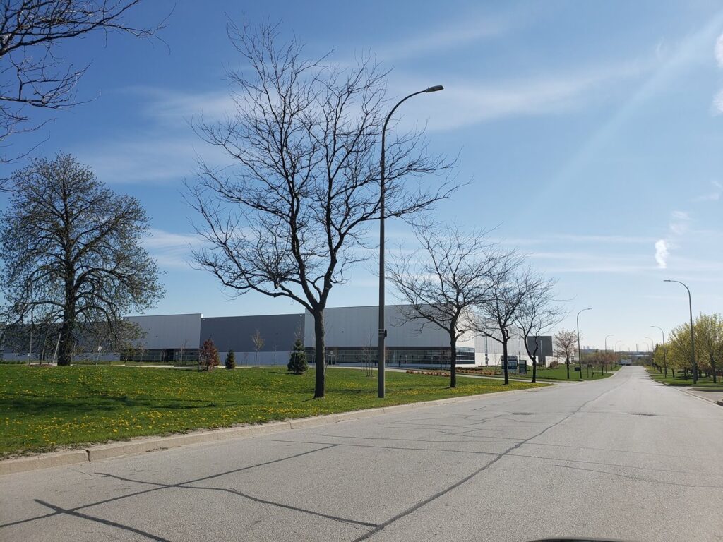 The road between the trees next to the warehouse