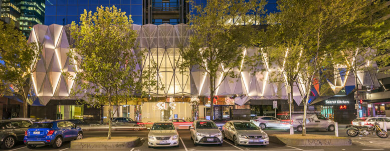 Cars in front of the illuminated entrance to a modern building