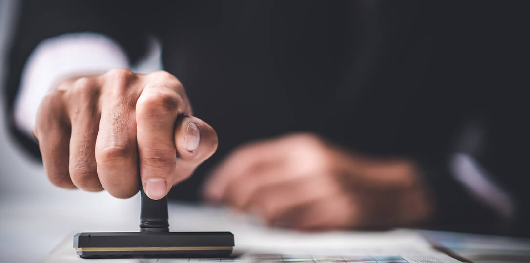 A hand holding a stamp stamping a document