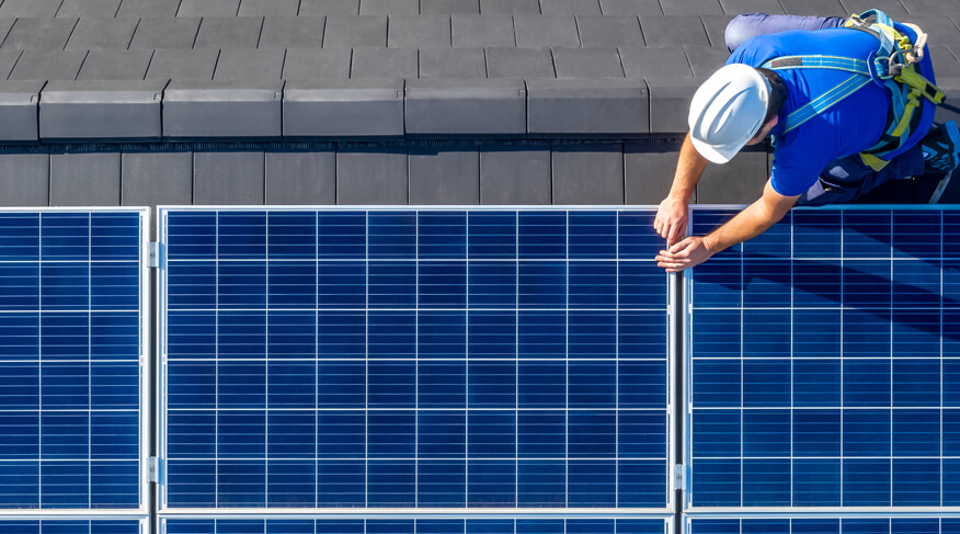 Worker installing photovoltaic panels on the roof