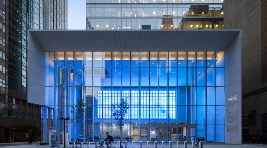 Riding cyclist in front of the entrance to a modern glass building