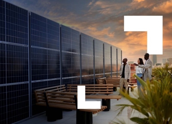 Three people are looking at solar panels on the roof of a building