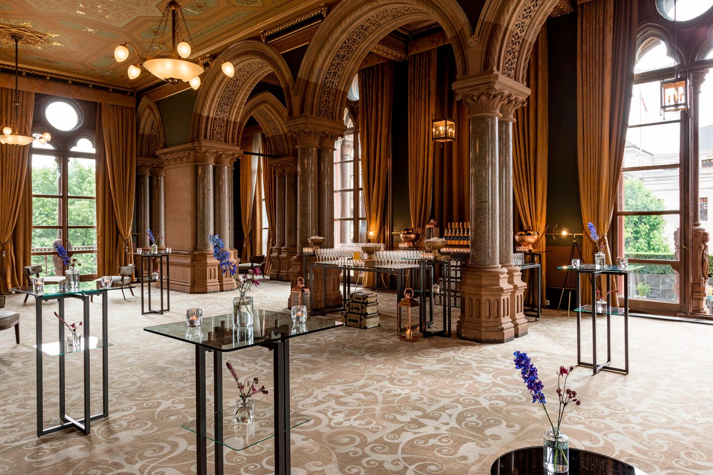 Ornate Victorian-era Ladies Smoking Room with arched windows, columns, and modern glass tables located in St Pancras Renaissance Hotel