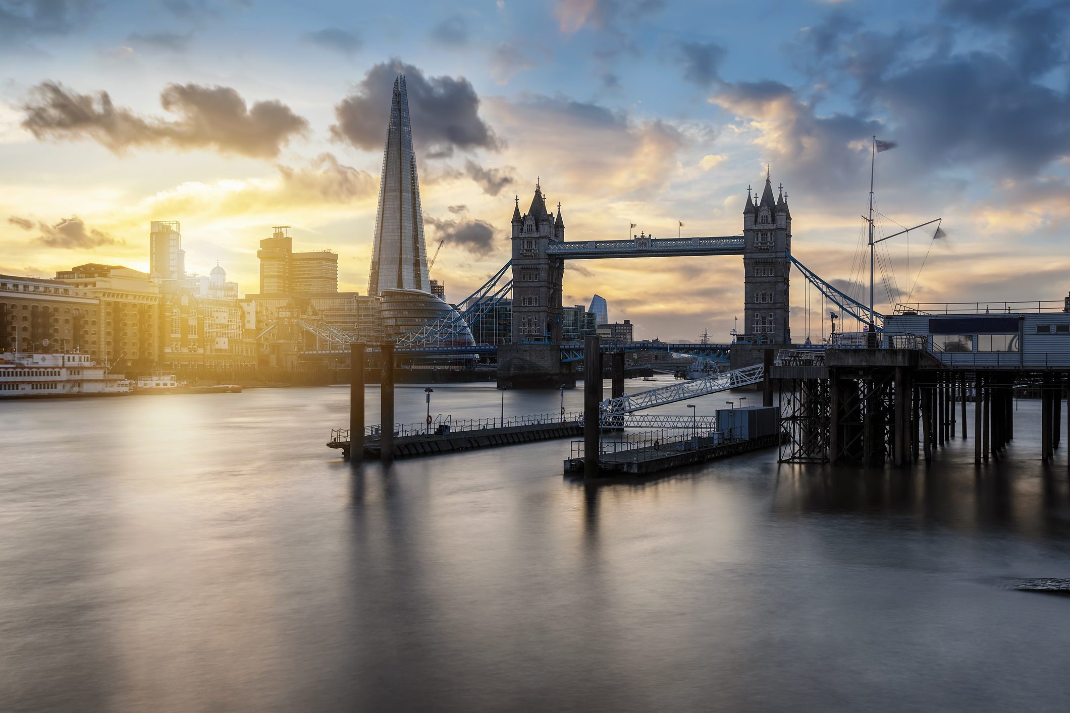 London skyline at sunset, featuring Tower Bridge in the foreground, the Shard skyscraper, and the River Thames.