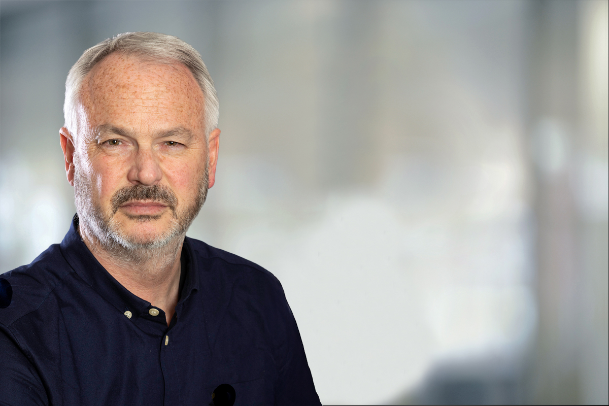 Portrait of Tim Marshall posing for the event agenda, with a grey blurred background.