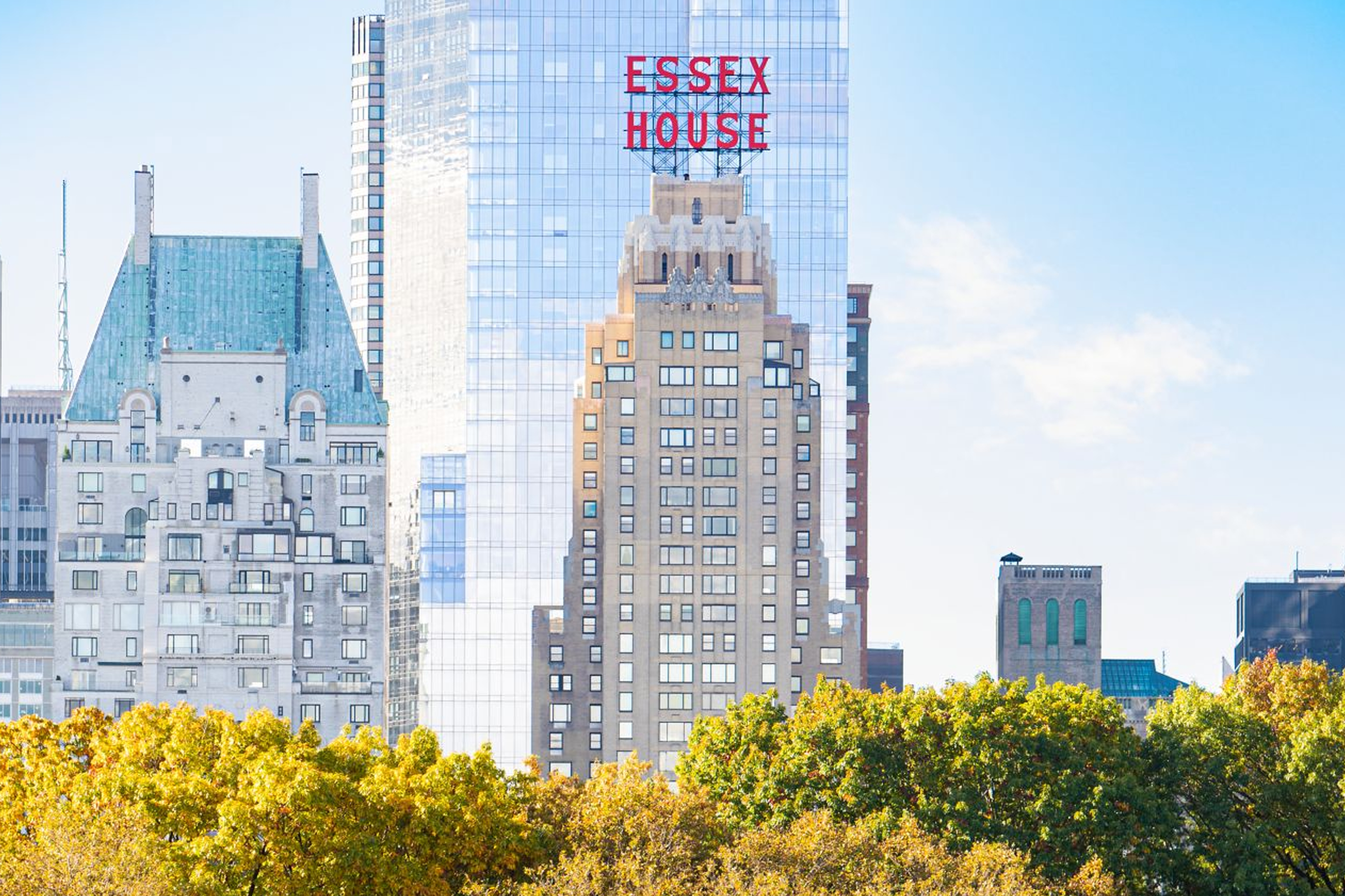 New York City skyline with Essex House visible, autumn trees in Central Park foreground.