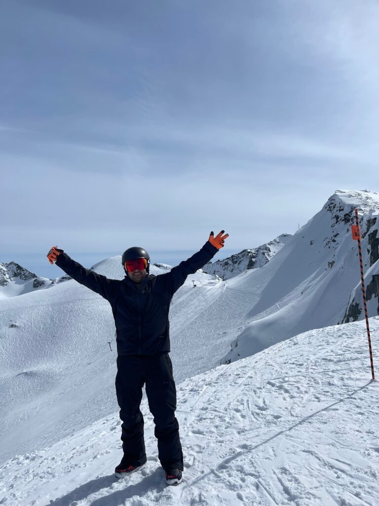 Trevor celebrating with raised arms while skiing on a snowy mountain slope